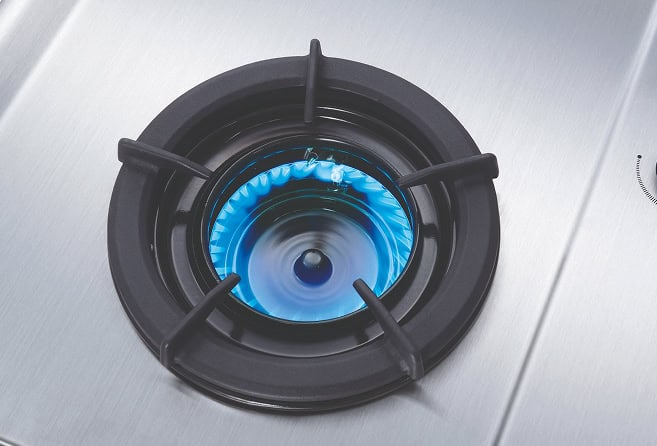 Stainless steel gas cooktop with three burners lit and blue flames, knobs centered toward the front, Rinnai branding visible on the left edge.
