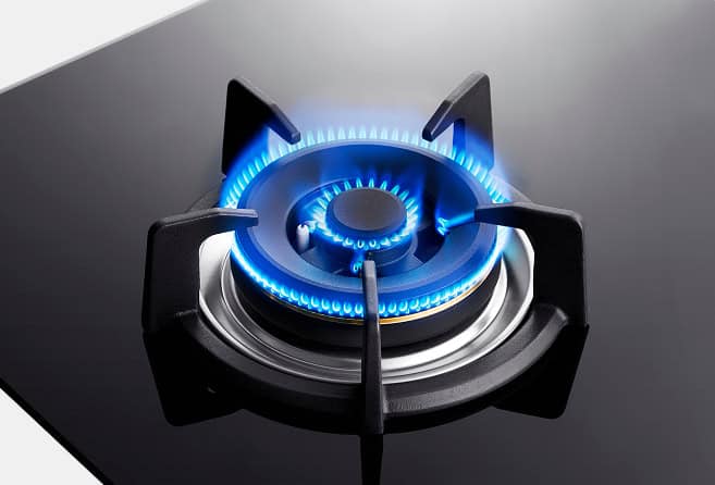 Two-burner black glass gas cooktop with blue flames lit and two central control knobs, modern kitchen appliance.