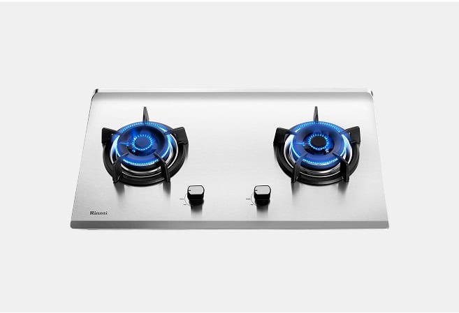 Two-burner stainless steel gas cooktop with lit blue flames and centered control knobs.