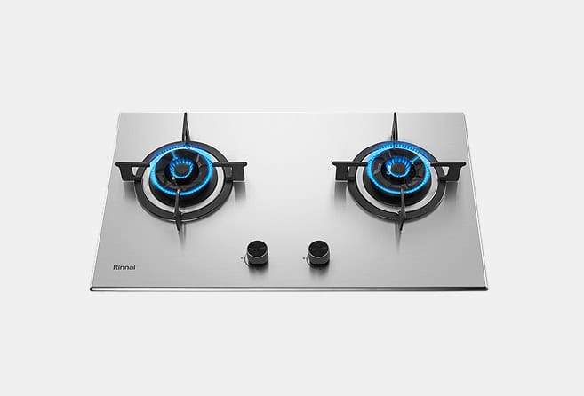 Stainless steel gas cooktop with two burners, each lit with blue flames, and two central control knobs (Rinnai logo visible). Administrative use only.