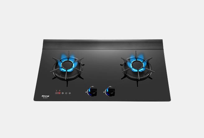 Two-burner gas hob with blue flames on a black glass surface and central control knobs.