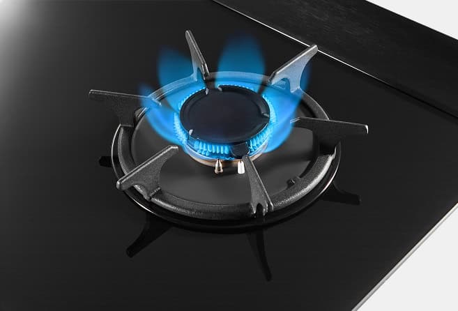 Two-burner gas hob with blue flames on a black glass surface and central control knobs.