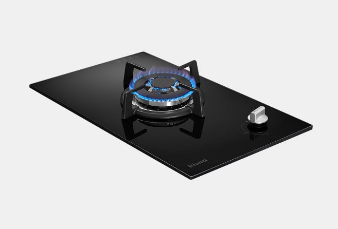Black glass gas cooktop with a single burner lit and a silver control knob on the right.