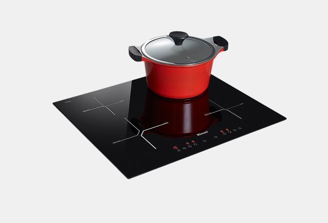 Red pot with a glass lid on a sleek black induction cooktop with touch controls visible at the front.