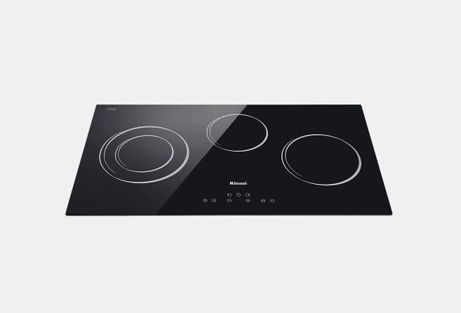 Black glass induction cooktop with three circular cooking zones and a central touch control panel.