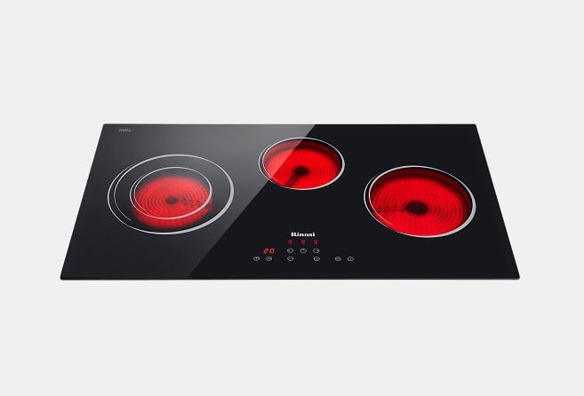 Black glass induction cooktop with three red-hot burners and center touch controls.