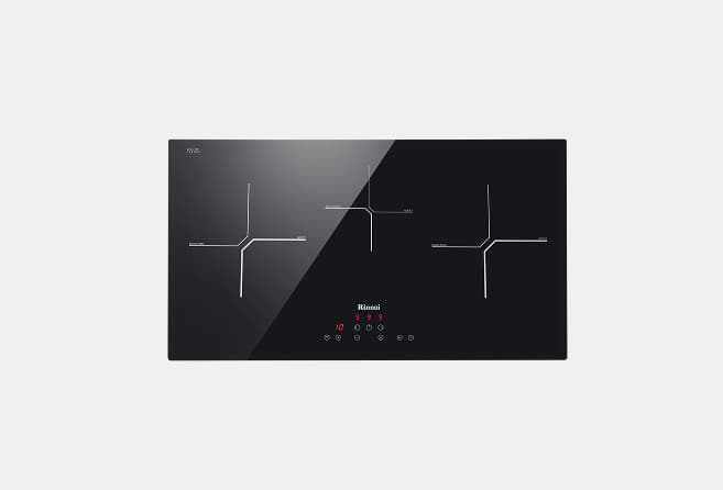 Black glass induction cooktop with three cross-shaped cooking zones, a diagonal split design, and a central touch-control panel.