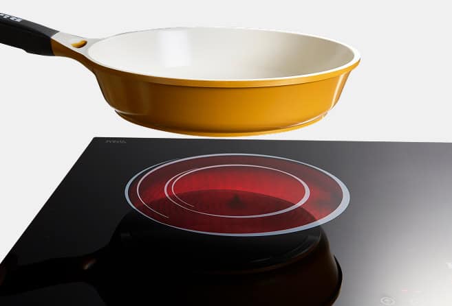 Orange nonstick frying pan hovering over a black glass electric stove with a red glowing circular heating element.
