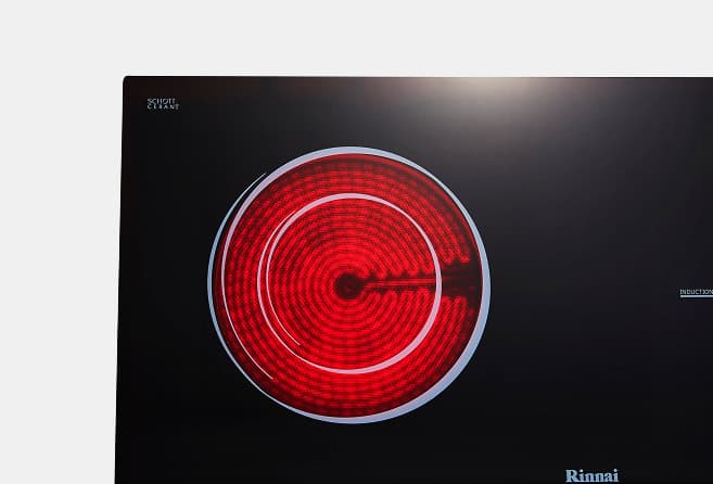 Close-up of a red circular induction burner element on a dark screen, with Rinnai logo in the corner.