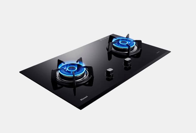 Black glass gas cooktop with two lit burners and control knobs on a sleek surface