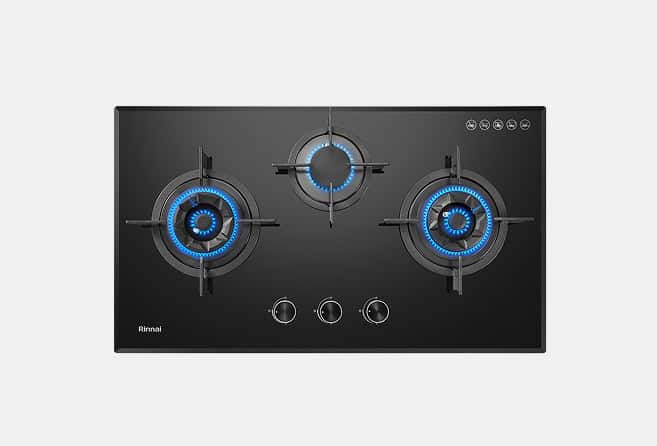Black glass gas cooktop with three burners and blue flame rings; front control knobs lined up in the center.