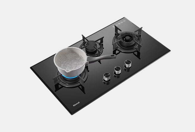 Gas cooktop with three burners; a pot boils on the left burner.