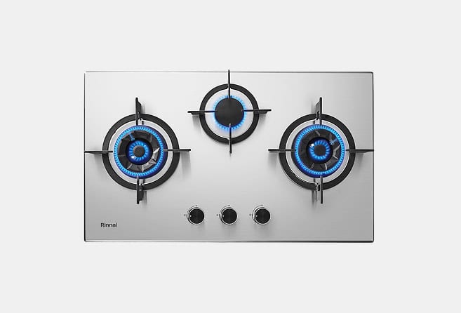 Three-burner stainless steel gas stove top with blue flames and three control knobs visible