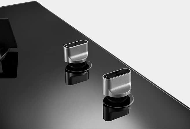 Two silver rotary knobs on a glossy black panel, reflecting nearby light and objects as part of a device control interface.