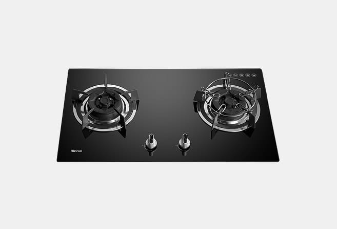 Black glass two-burner gas cooktop with dual knobs in the center and circular metal burner rings; brand 'Rinnai' visible in the lower-left corner