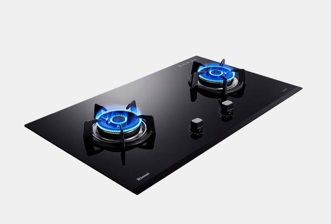 Black glass gas cooktop with two lit burners and control knobs on the right side to adjust heat.