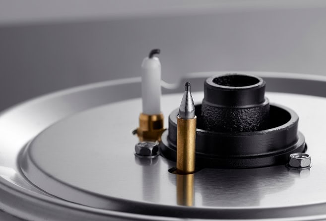 Close-up of a turntable platter with the tonearm and stylus ready to play a vinyl record surface on a reflective metal surface.