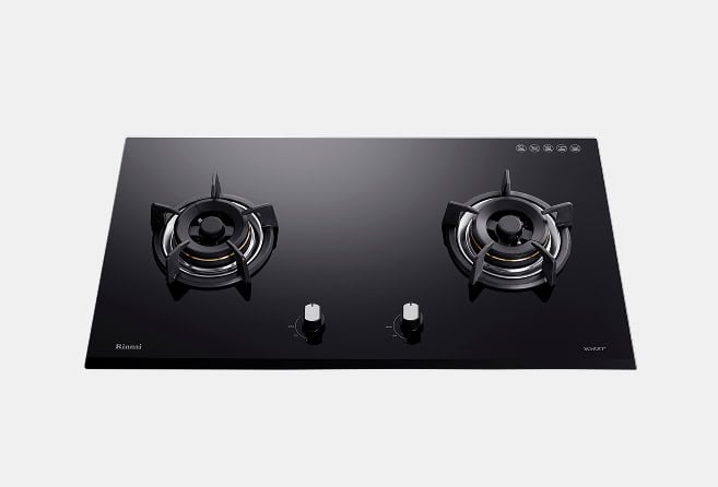 Black glass two-burner gas cooktop with central control knobs and metal burner grates from above.