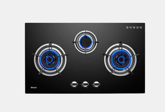 Black glass gas cooktop with three lit burners (blue flames) and three control knobs in the center, Rinnai branding bottom left.