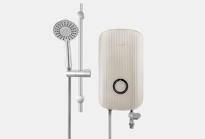 Beige wall-mounted electric water heater with a circular control dial beside a chrome handheld shower and flexible hose system