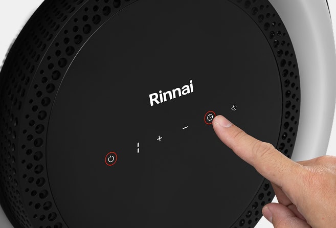 Close-up of a finger pressing the power/menu button on a black Rinnai control panel.