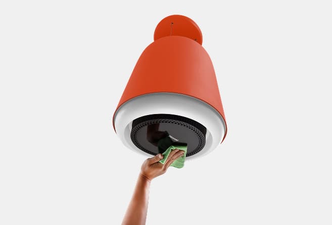Person cleaning a red pendant ceiling lamp with a green cloth from below.