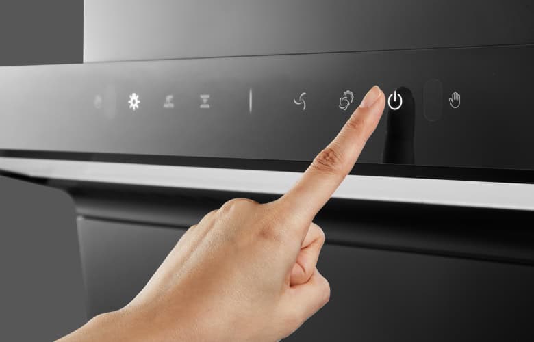 Person's index finger pressing the power button on a modern appliance control panel.