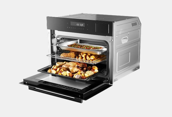 Stainless steel countertop oven with the door open, showing roasted chicken and vegetables on two racks with a digital control panel above.