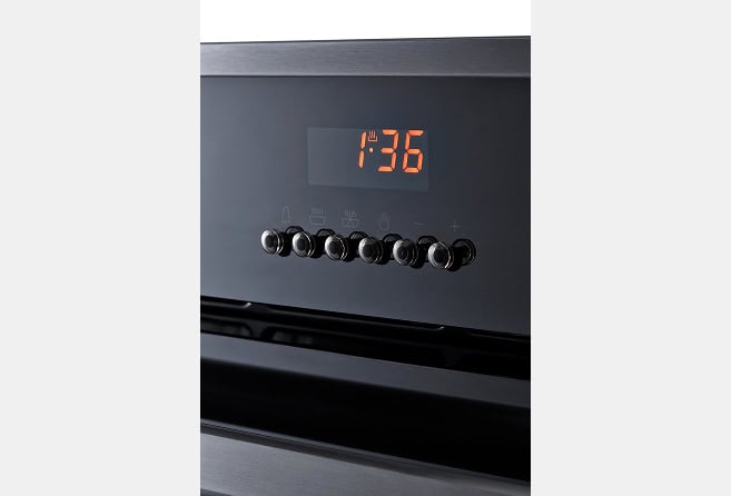 Electric oven with black control knobs and a digital clock showing 1:36, stainless steel front.