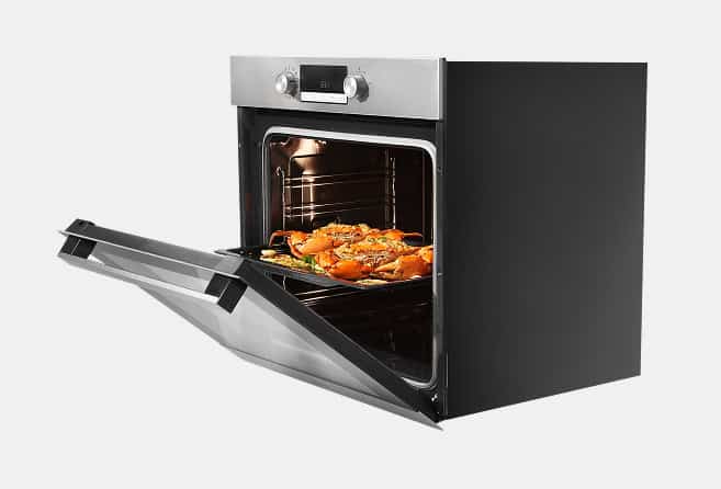 Black built-in oven with its door open, showing a roasting tray of chicken inside.