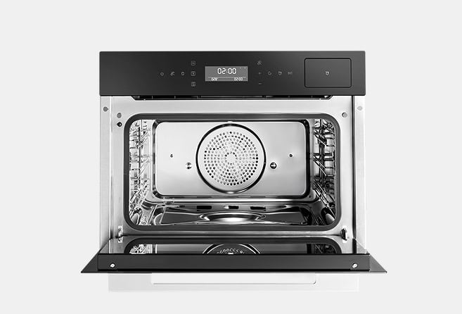 Open oven with a stainless steel interior and a circular perforated tray in the center; black control panel on top with a digital display.