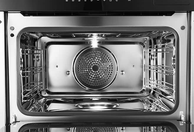 Stainless steel oven interior with chrome racks on both sides and a circular back heating element/fan.