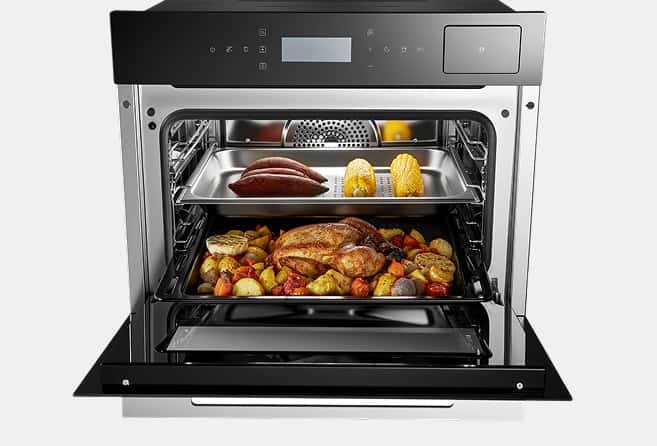 Electric oven with roasted chicken, potatoes, and vegetables visible on multiple racks inside.