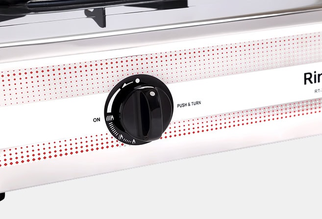 Close-up of a black gas grill control knob on a white panel with red dotted design, showing the ON position and 'Push & Turn' instruction.