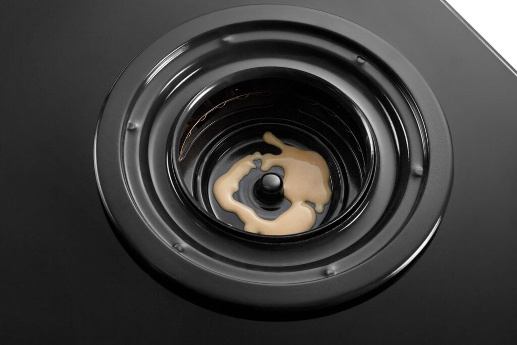 Close-up of a black, circular, layered component with a beige liquid pooled in the center.