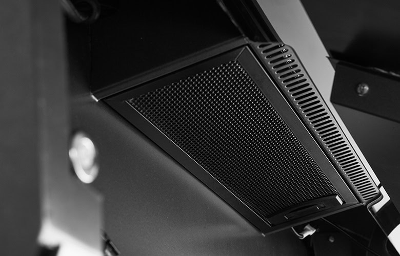 Close-up of a perforated metal vent/grille on dark equipment photographed at an angle.