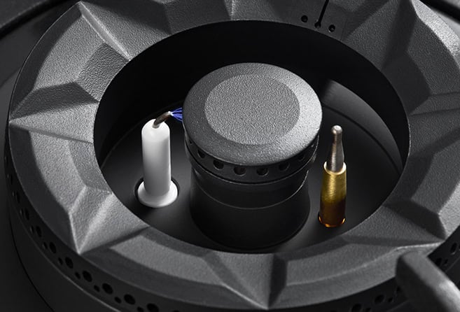Close-up of a loudspeaker driver showing the cone, voice coil housing, and binding posts with white and gold terminals.